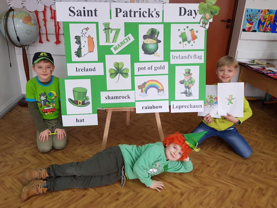 Dzieci przebrane na zielono, na tle prac z okazji Dnia Św. Patryka