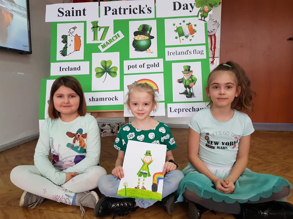 Dzieci przebrane na zielono, na tle prac z okazji Dnia Św. Patryka