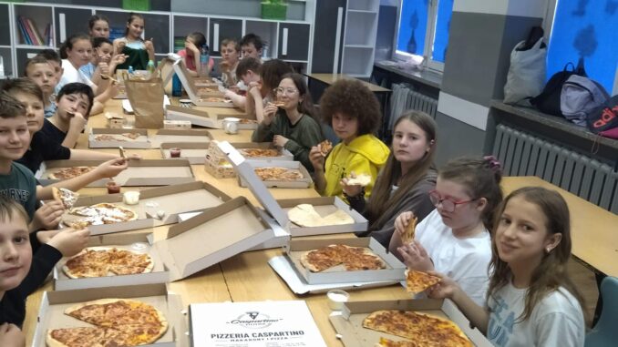 Uczniowie jedzą pizzę